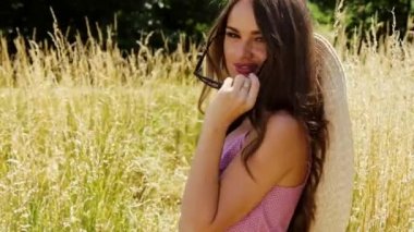 Güzel genç seksi kadın uzun saçları parlak makyaj doğa arka plan manzara kuru spike çim ve ağaç bahçe Yaz modeli pamuk elbise aksesuar hasır şapka güneş gözlüğü moda tarzı giyinmiş.