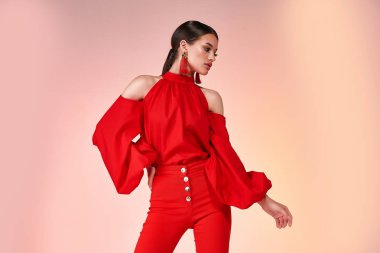 Çok güzel, seksi, zarif bir kadın manken pozu. Kırmızı renk pantolon, ipek bluz giyin. Parti için yaz makyajı, saç stili, esmer, aksesuar, mücevher stüdyosu..