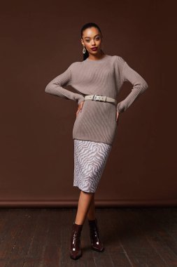 Seksi güzel kadın, bronz tenli, bej örülü elbise giyiyor.