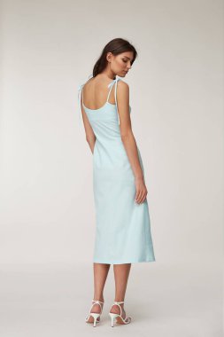 Güzel bir kadın yüzü esmer, esmer, ten renginde, moda yaz koleksiyonu organik pamuk, açık mavi, ince elbise tarzı romantik randevu yürüyüşü, aksesuar ayakkabılar..