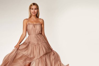 Çok güzel seksi bir kadın ten rengi ten rengi ten rengi ten rengi ten rengi vücut modeli pozu uzun bej rengi ipek elbise giyme yaz partisi elbise makyaj malzemesi saç stili sarı mücevher stüdyosu.
