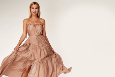 Çok güzel seksi bir kadın ten rengi ten rengi ten rengi ten rengi ten rengi vücut modeli pozu uzun bej rengi ipek elbise giyme yaz partisi elbise makyaj malzemesi saç stili sarı mücevher stüdyosu.