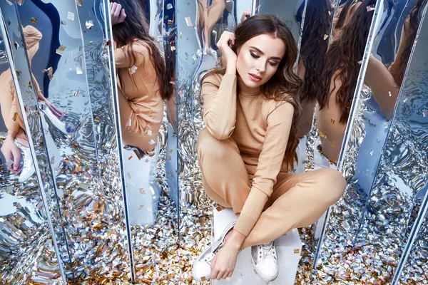 Seksi güzel kadın uzun kıvırcık esmer saçlar günlük rahat kıyafetler giyer her gün örgü yün kaşmir spor ayakkabılar güzel makyaj aynası ve pullu partiler için iyi eğlenceler.