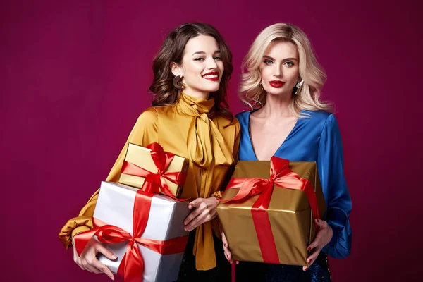 Two beautiful sexy young woman bright evening make-up red lips long fluffy eyelashes hold gift box holiday New Year  joy fun happy merry Christmas Eve party celebration St. Valentine\'s Day girlfriend.