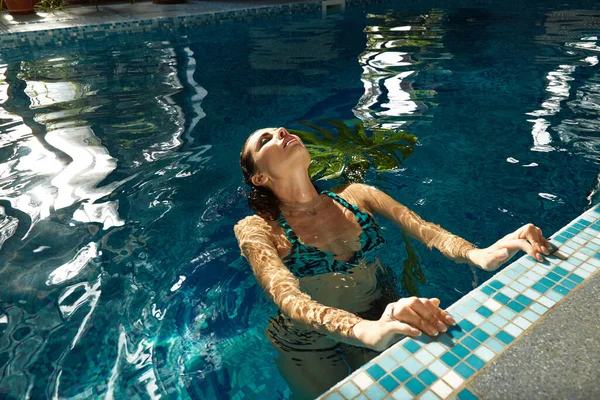 在游泳池游泳的女人漂亮性感的女士身材晒黑的皮肤阳光在蓝色海滨度假宾馆温泉疗养地海滨热带棕榈树收集时尚泳衣 — 图库照片