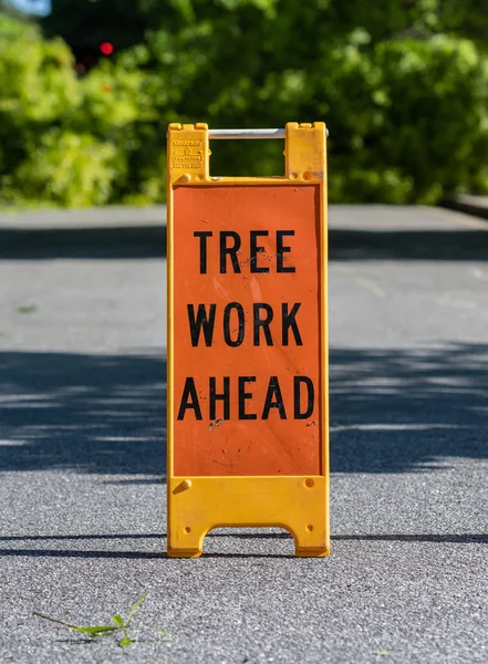 在郊区街道上的树工作前折叠标志 — 图库照片