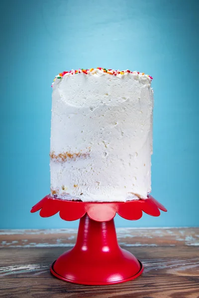 高蛋糕霜简单的顶部红色蛋糕站在蓝色背景前 — 图库照片