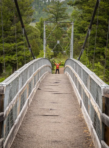 Man Holds up Arms Across Suspension Bridge — Stock Photo, Image