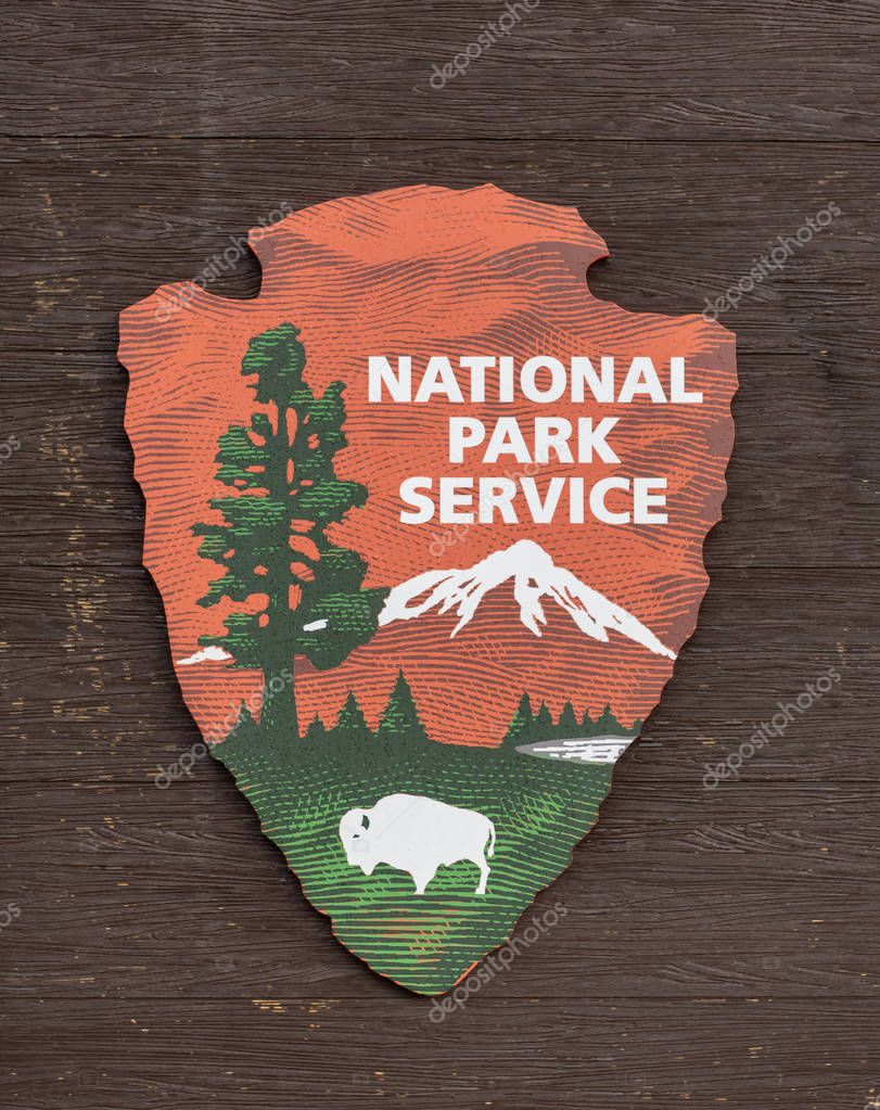 June 23, 2018: Gardiner, United States: National Park Service Logo on Wooden Background