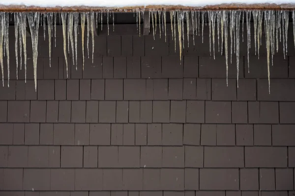 Eiszapfen hängen über brauner Wand — Stockfoto