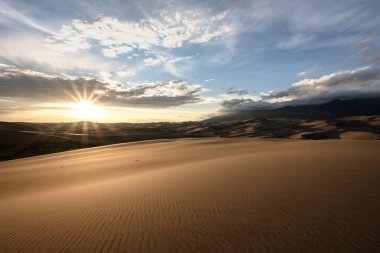 Kum tepelerinin üzerinde Bulutlu Dağlar