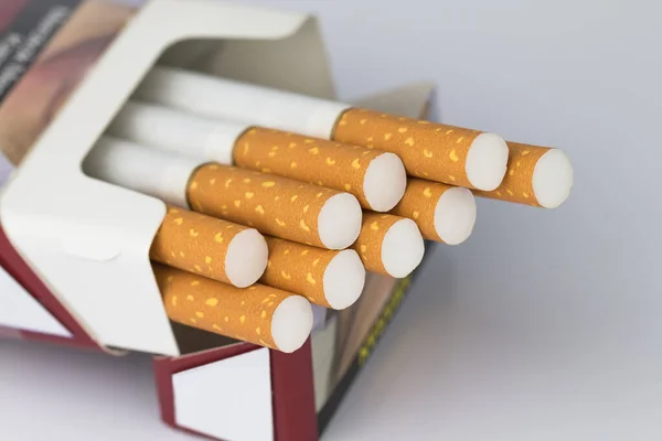 Sigara paketleri kırmızı kağıt zarflara paketlenmiş sigara ucu veya sigara ucu kahverengidir ve ucu beyazdır ve sigara ya da sigara ucunun ucu beyaz yüzeydeki paketin ötesine uzanır..