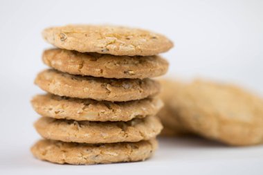 Mısır gevreği kurabiyeleri birkaç parçanın üzerine istiflenir ve arkasında üç parça bulunur, ve kurabiyeler kahverengidir ve resmin nesnenin yanında boş bir alan vardır ve beyaz bir arka planı vardır.