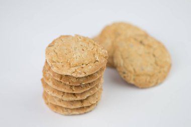 Mısır gevreği kurabiyeleri birkaç parçanın üzerine istiflenir ve arkasında üç parça bulunur, ve kurabiyeler kahverengidir ve resmin nesnenin yanında boş bir alan vardır ve beyaz bir arka planı vardır.