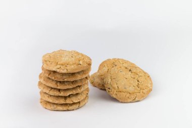 Mısır gevreği kurabiyeleri birkaç parçanın üzerine istiflenir ve arkasında üç parça bulunur, ve kurabiyeler kahverengidir ve resmin nesnenin yanında boş bir alan vardır ve beyaz bir arka planı vardır.