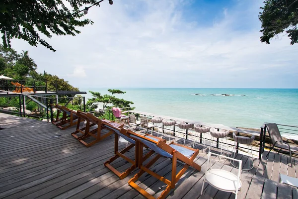 Wooden chair for sitting on the beach Set aside a seat for a resting point or a viewpoint near the beach with green trees On a day of turquoise waters and clear skies and beautiful clouds