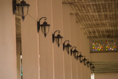 Eski tarz vintage binanın içinde sütunlarla süslenmiş birçok lamba. Görüntü çok net değil..