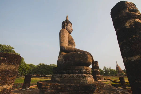 Tapınaktaki büyük Buda heykeli Sukhothai Tarihi Parkı 'nda görkemli bir şekilde duruyor. Akşamları, turuncu renkli gökyüzünün ortasında Tayland 'ın Sukhothai Eyaleti.