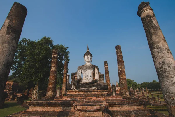 Tapınaktaki büyük Buda heykeli Sukhothai Tarihi Parkı 'nda görkemli bir şekilde duruyor. Akşamları, turuncu renkli gökyüzünün ortasında Tayland 'ın Sukhothai Eyaleti.