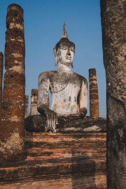 Tapınaktaki büyük Buda heykeli Sukhothai Tarihi Parkı 'nda görkemli bir şekilde duruyor. Akşamları, turuncu renkli gökyüzünün ortasında Tayland 'ın Sukhothai Eyaleti.