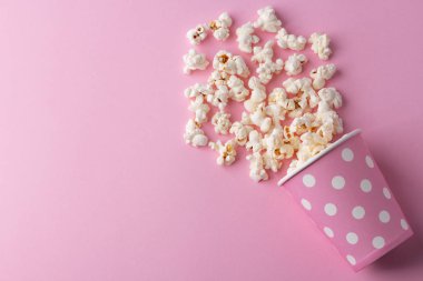 Pembe arka planda patlamış mısır, sinema, sinema ve eğlence konsepti