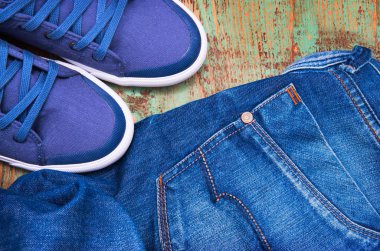 Yere atılmış bir çift kot ve bir çift spor ayakkabı.