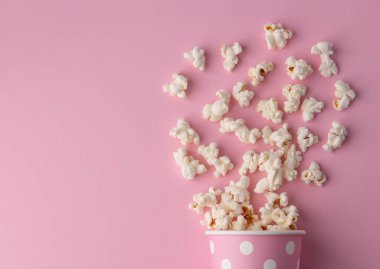 Pembe arka planda patlamış mısır, sinema, sinema ve eğlence konsepti