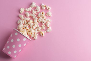 Pembe arka planda patlamış mısır, sinema, sinema ve eğlence konsepti