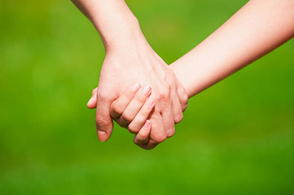 Mother holding a hand of his son in summer day outdoors