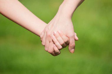 Anne, yaz günü açık havada oğlunun elini tutuyor.