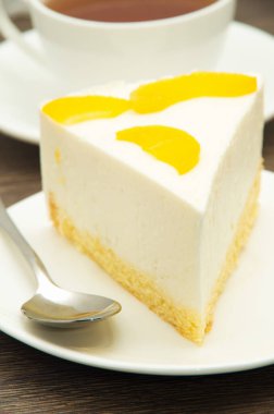 Beyaz tabakta şeftalili cheesecake.