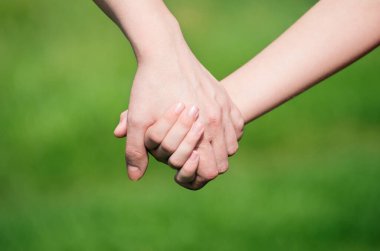 Anne, yaz günü açık havada oğlunun elini tutuyor.