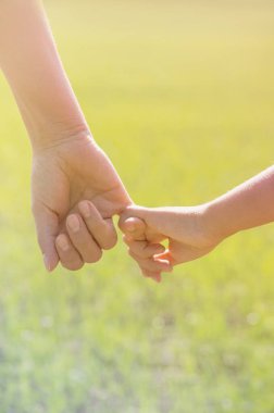 Anne, yaz günü açık havada oğlunun elini tutuyor.