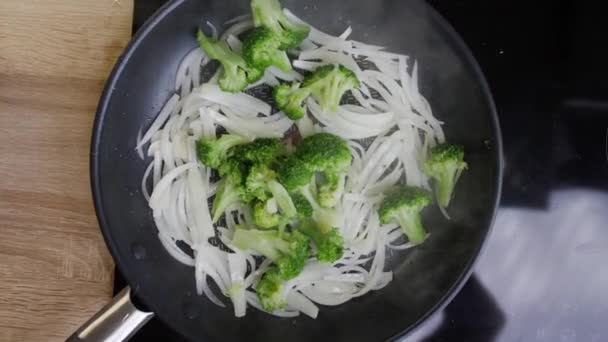 Onions, broccoli and beans are fried in a pan — Stock Video