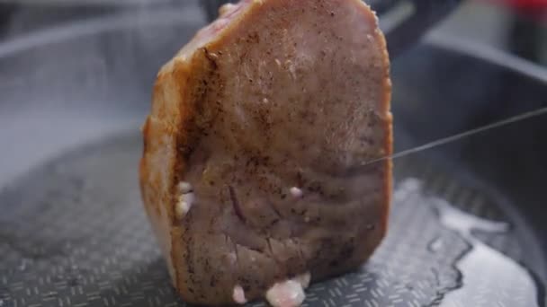 Um pedaço de atum é frito no lado em óleo em uma frigideira, fumaça de óleo — Vídeo de Stock