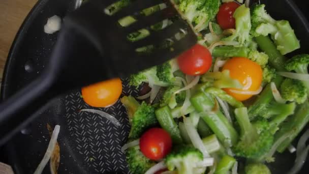Cebollas, brócoli y frijoles verduras se cocinan en una sartén, ver desde arriba — Vídeo de stock
