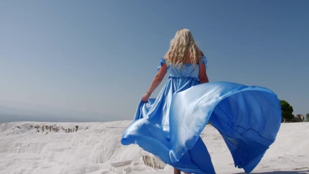 在Pammukale 一个身穿蓝色衣服的女孩沿着白色岩石散步 — 图库视频影像