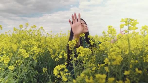 一个迷人的女孩在开花的田野里抚摸着她的头发 唱着歌 动作优美 抚摸着黄色的花朵 穿着绿色长裙的布鲁内特 — 图库视频影像