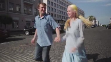 Sevimli genç çift yol boyunca koşar ve sevinir..