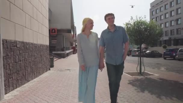 Una joven pareja caminando por una calle de la ciudad . — Vídeos de Stock