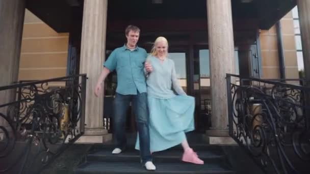 Una joven pareja desciende juguetonamente las escaleras . — Vídeos de Stock