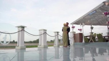 Doğaya tepeden bakan bir restoranda dans eden genç bir çift..