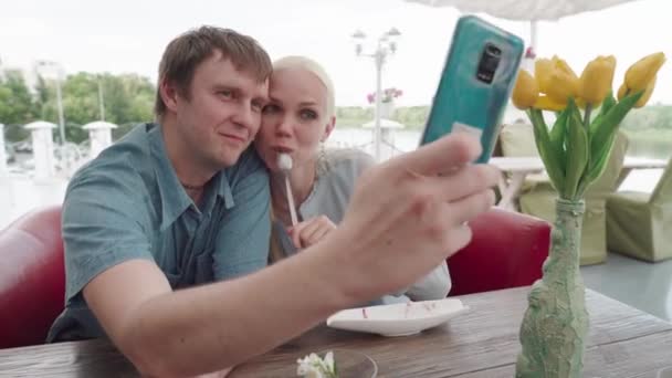 Pasangan yang cantik mengambil foto selfie di kafe musim panas. — Stok Video