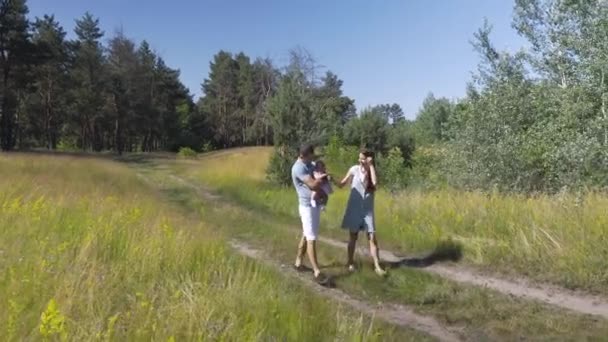 Uma jovem família com um bebê andando na natureza . — Vídeo de Stock