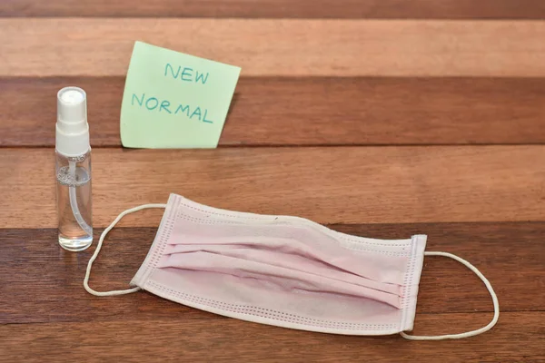 Face mask with sanitizer on wooden background. New normal concept image