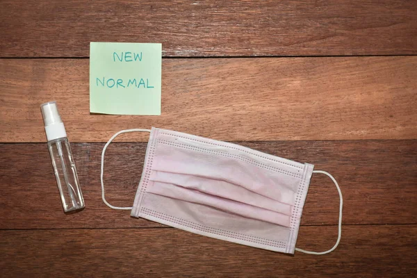 Face mask with sanitizer on wooden background. New normal concept image