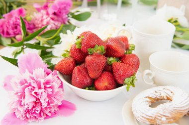 Taze çilek, bir fincan çay, pione ve ekler. Üst Manzara. Yatay olarak. Güzel bir sabah kahvaltısı..