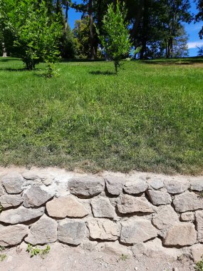 Alçak taş duvar ve yeşil çayır.