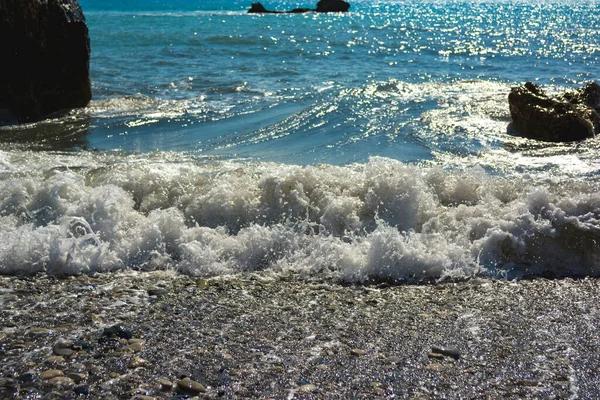 sea foam of a sea wave rolling on a sandy shore on a clear sunny day