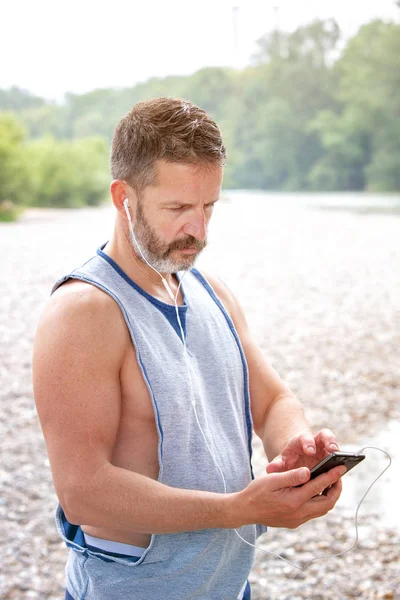 yakışıklı sakallı atlet açık havada seyir onun telefon portresi